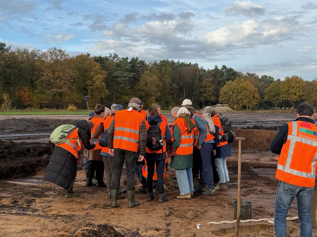 deelnemers staan rond de archeoloog